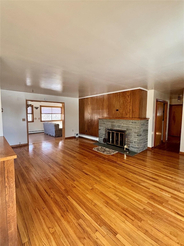 unfurnished living room featuring a glass covered fireplace, light wood-style flooring, baseboards, and a baseboard radiator