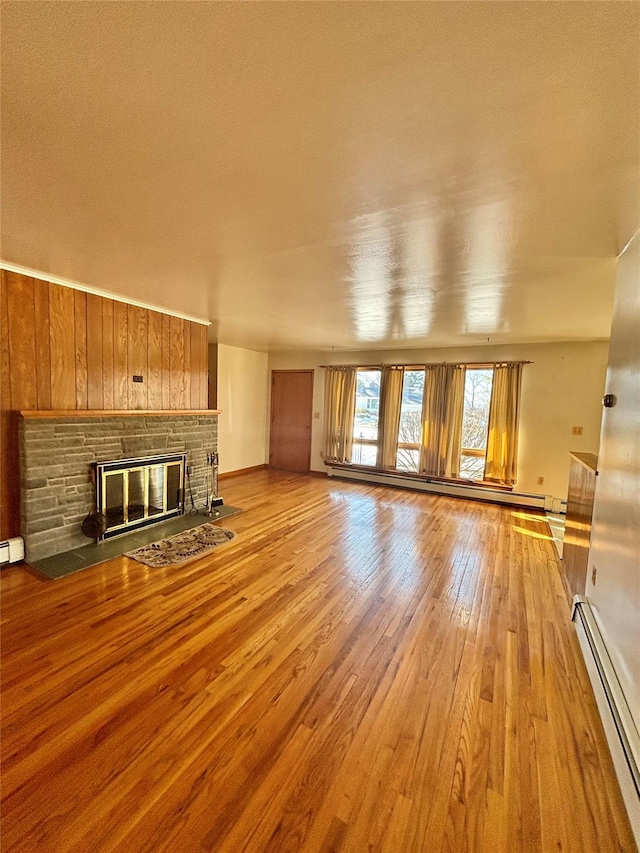 unfurnished living room featuring light wood-style floors, a baseboard radiator, and a fireplace