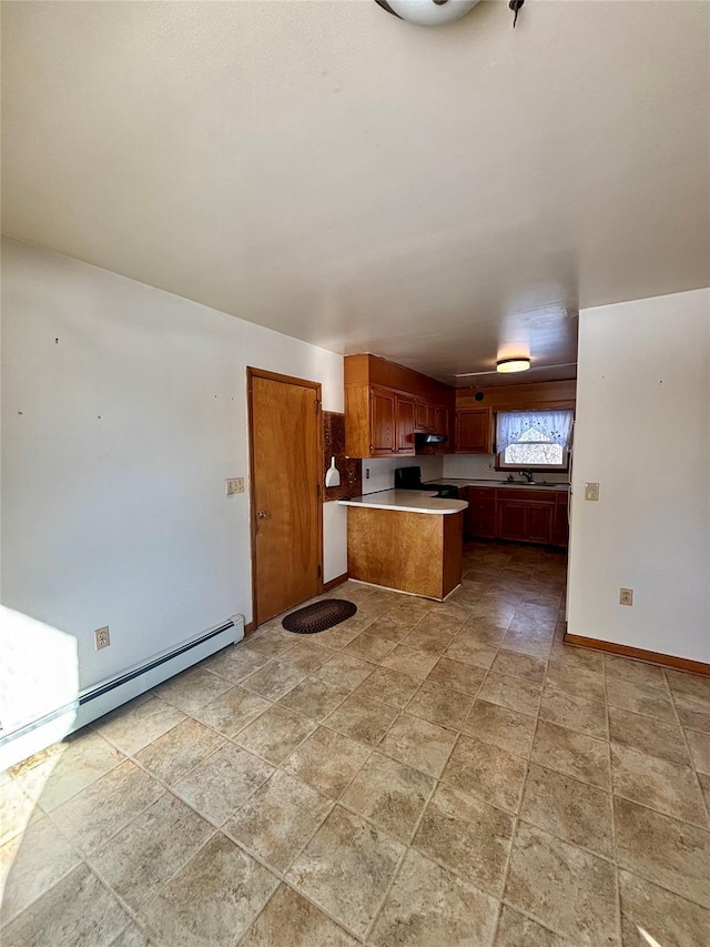 kitchen with baseboards, brown cabinetry, open floor plan, a peninsula, and light countertops