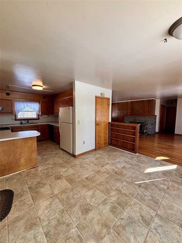 kitchen with visible vents, baseboards, light countertops, freestanding refrigerator, and brown cabinets