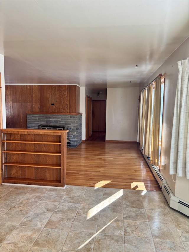 unfurnished living room with a fireplace, a baseboard radiator, and wood finished floors