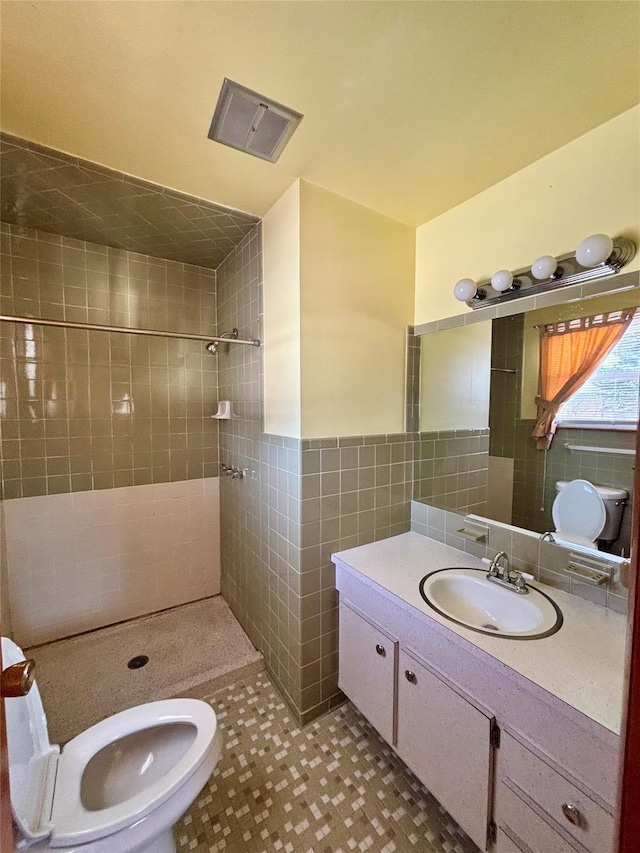 full bathroom with tile walls, visible vents, wainscoting, a shower stall, and vanity