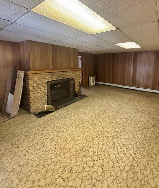 finished basement with a paneled ceiling, wood walls, and a fireplace