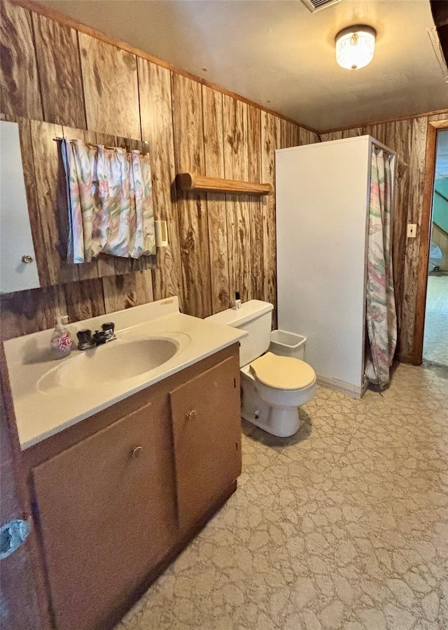 bathroom featuring toilet, wooden walls, vanity, and tile patterned floors