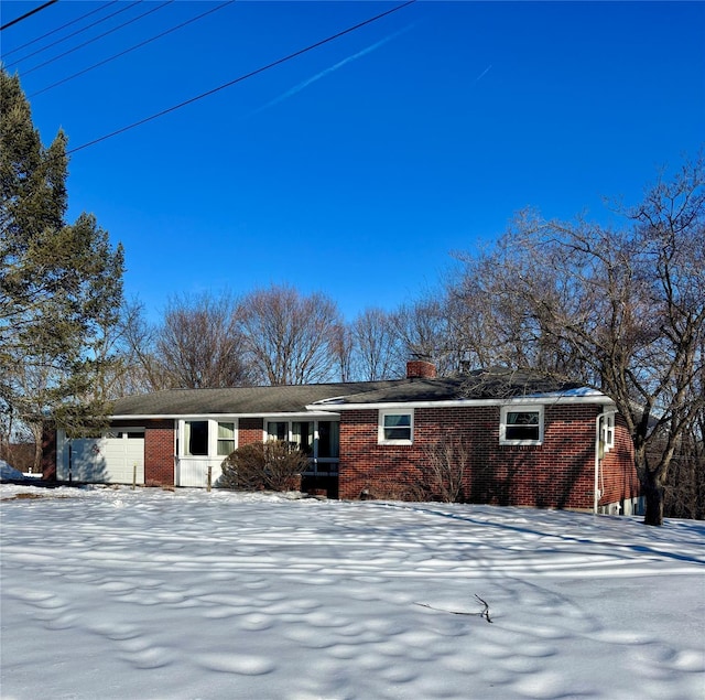 view of front facade featuring brick siding, a chimney, and an attached garage