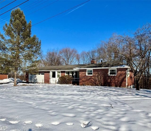 single story home with a garage, brick siding, and a chimney