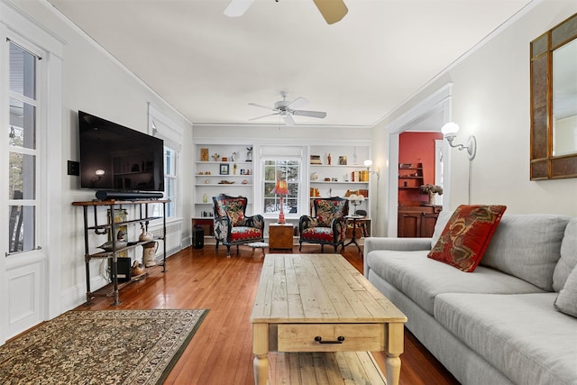 living room featuring ornamental molding, hardwood / wood-style floors, built in features, and ceiling fan