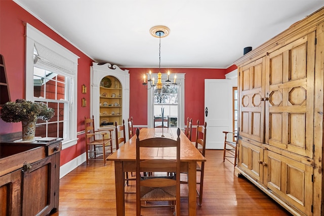 dining room featuring ornamental molding, light hardwood / wood-style floors, and a notable chandelier