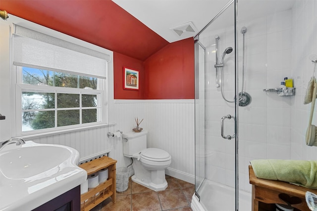 bathroom featuring a shower with shower door, lofted ceiling, tile patterned flooring, vanity, and toilet