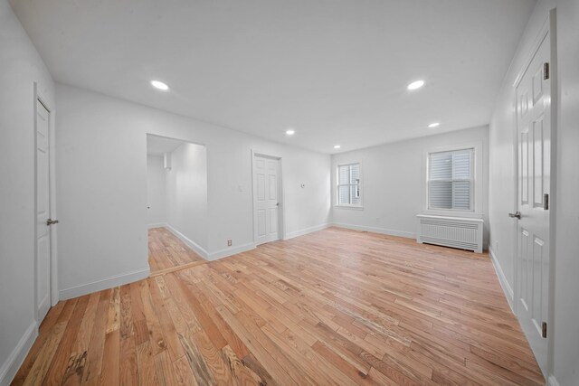 interior space featuring radiator heating unit and light hardwood / wood-style floors