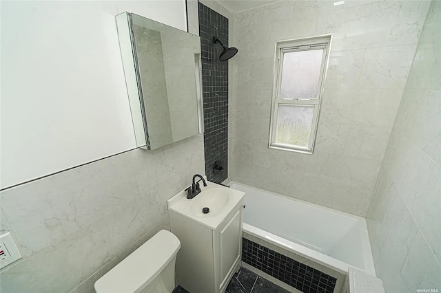 full bathroom featuring vanity, tiled shower / bath, tile walls, and toilet