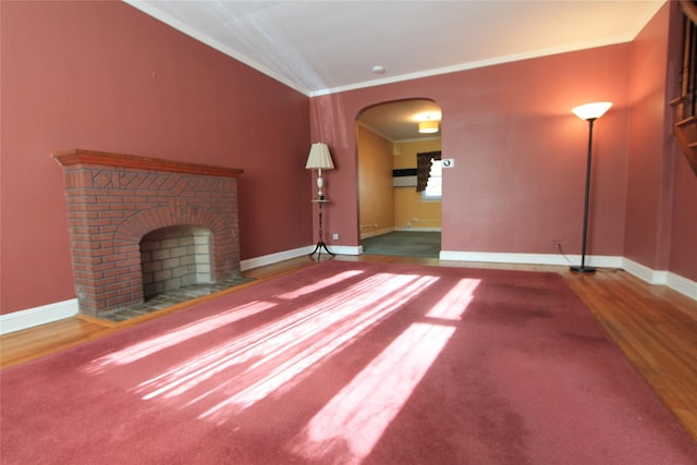 unfurnished living room featuring ornamental molding, a brick fireplace, and wood-type flooring