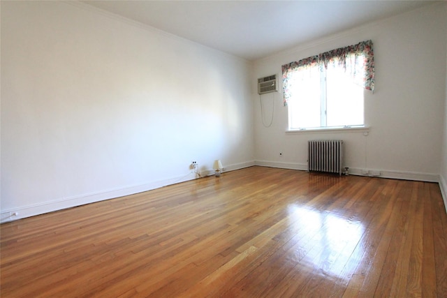 unfurnished room featuring hardwood / wood-style flooring, a wall mounted AC, and radiator heating unit