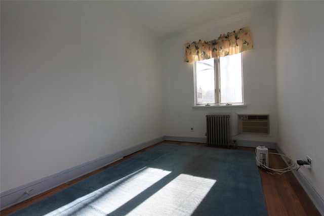 spare room with a wall unit AC, radiator heating unit, and dark hardwood / wood-style flooring