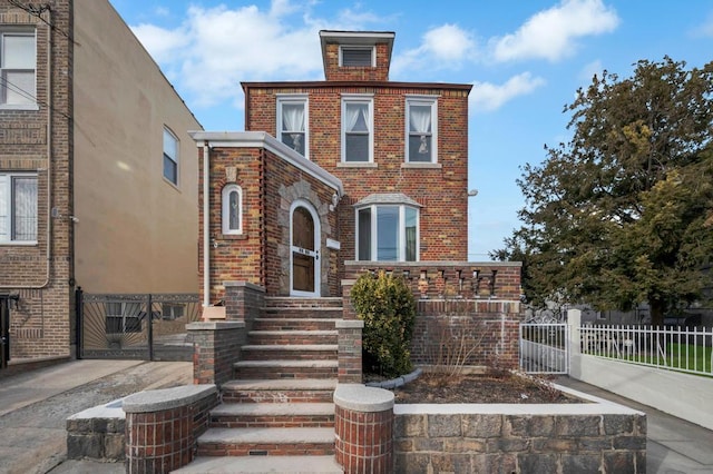 view of front of property with brick siding, fence, and a gate