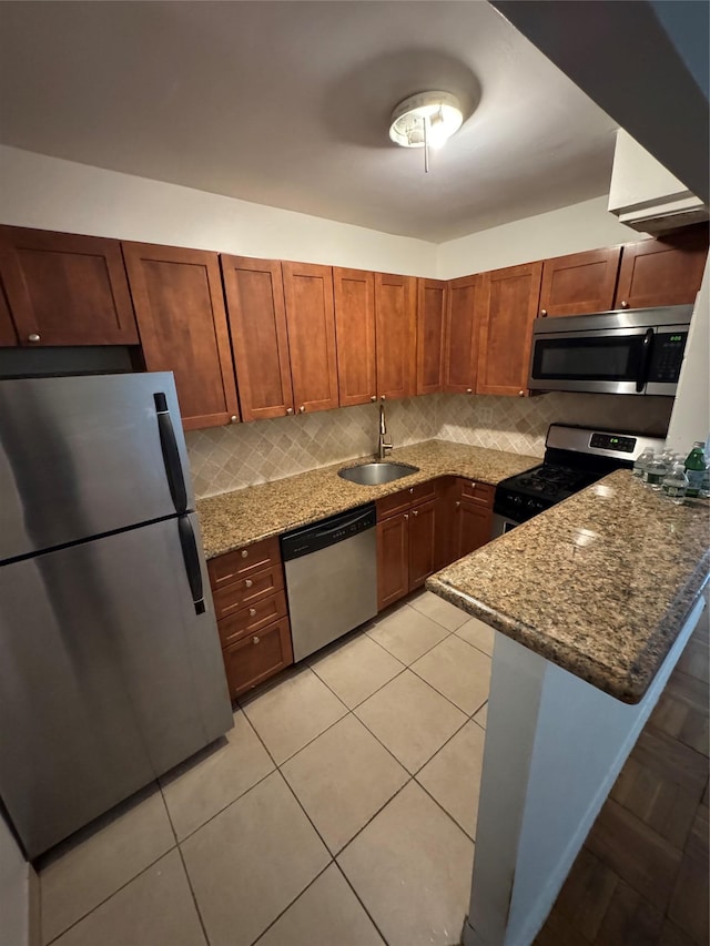 kitchen featuring sink, stainless steel appliances, kitchen peninsula, and stone countertops