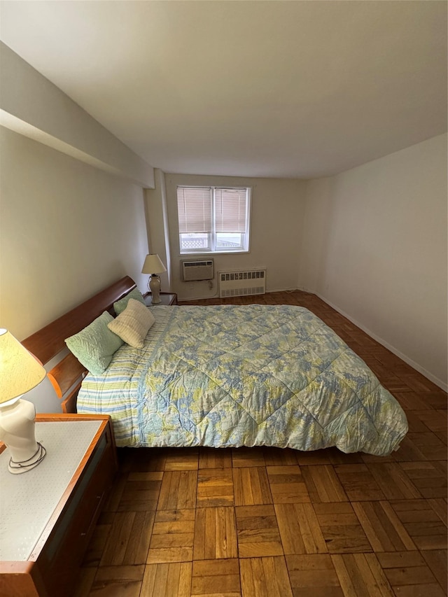 bedroom with parquet floors, radiator heating unit, and an AC wall unit