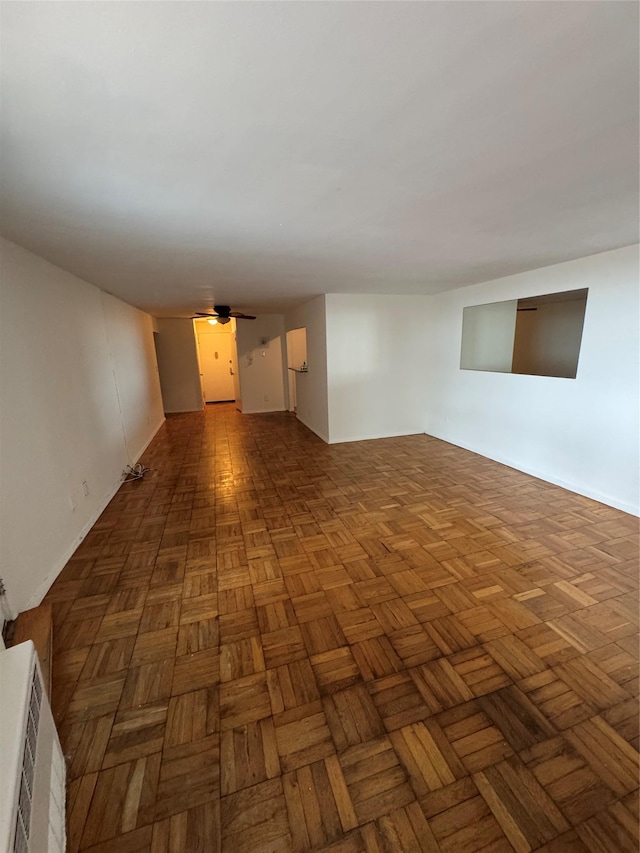 spare room featuring ceiling fan and dark parquet floors