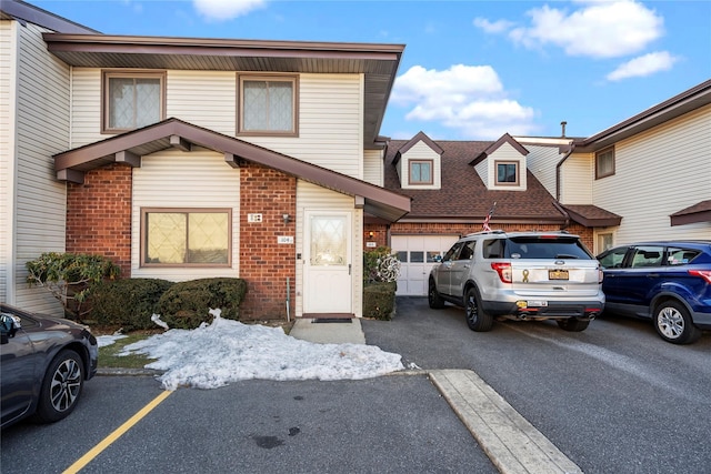 townhome / multi-family property featuring a garage, brick siding, and aphalt driveway