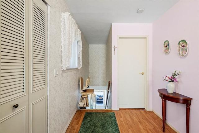 hall featuring light wood-type flooring and baseboards