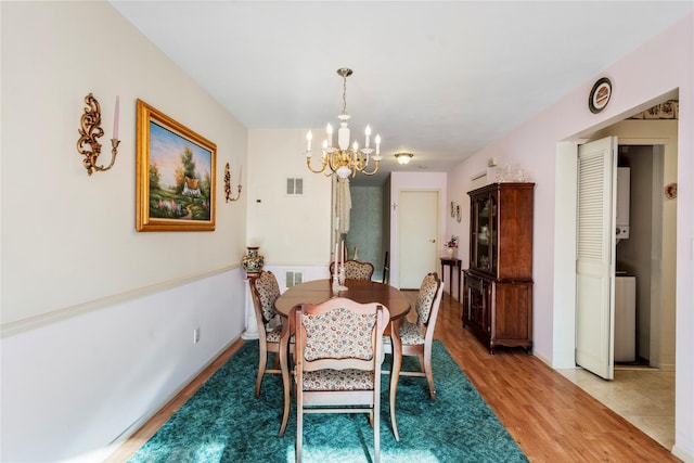 dining area with a chandelier, wood finished floors, visible vents, and baseboards