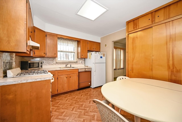 kitchen with light parquet flooring, stainless steel appliances, sink, and backsplash