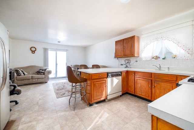 kitchen with sink, a breakfast bar area, backsplash, kitchen peninsula, and stainless steel appliances