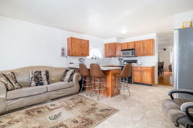 kitchen with stainless steel appliances, kitchen peninsula, a breakfast bar area, and backsplash