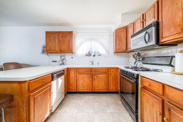 kitchen featuring sink, light tile patterned floors, kitchen peninsula, stainless steel appliances, and decorative backsplash