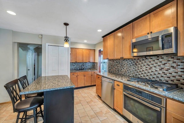 kitchen featuring appliances with stainless steel finishes, a kitchen bar, light stone countertops, and a kitchen island