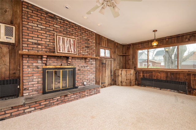 unfurnished living room with wood walls, radiator heating unit, a fireplace, and a healthy amount of sunlight