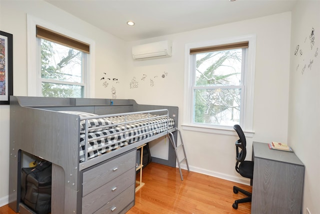 bedroom with light wood-type flooring and a wall unit AC