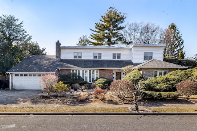 traditional-style home featuring concrete driveway, a chimney, and an attached garage