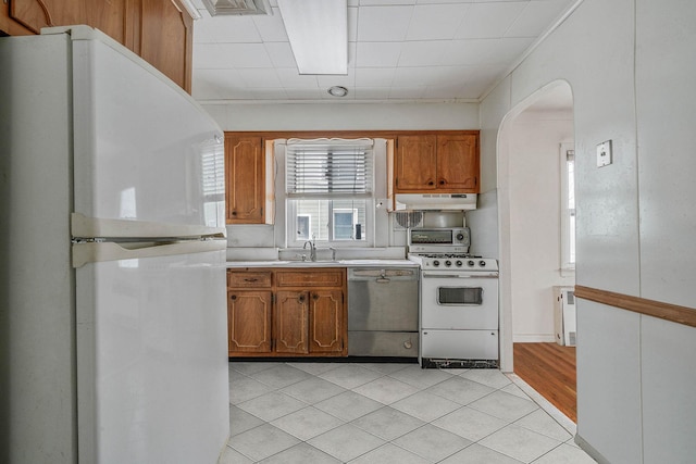 kitchen with radiator heating unit, sink, light tile patterned floors, and white appliances