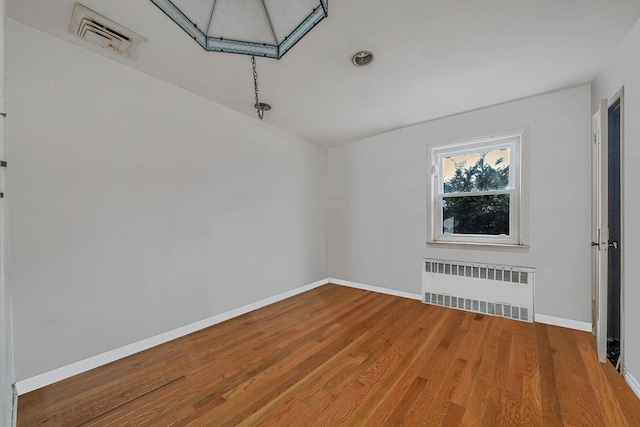 spare room featuring wood-type flooring and radiator