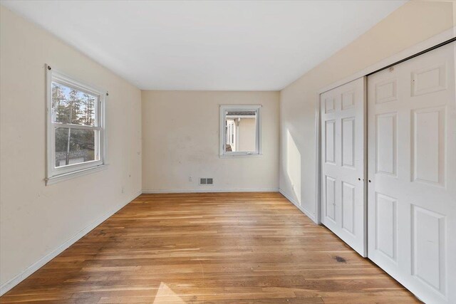 313 Sixth Ave, Pelham, NY 10803 - unfurnished bedroom with multiple windows, a closet, and light wood-type flooring