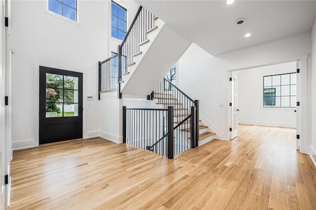 foyer featuring baseboards, stairway, and light wood-style floors