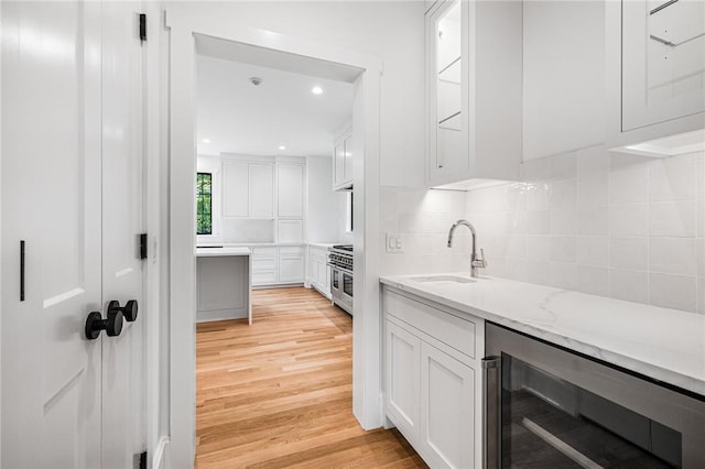 kitchen featuring beverage cooler, white cabinets, and stainless steel stove