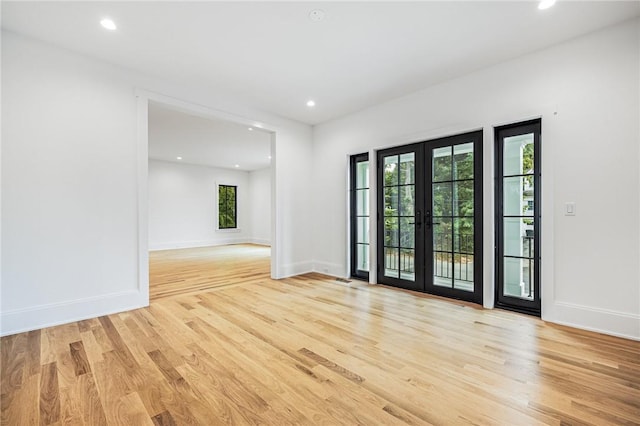 unfurnished room with light wood finished floors, baseboards, a wealth of natural light, and french doors