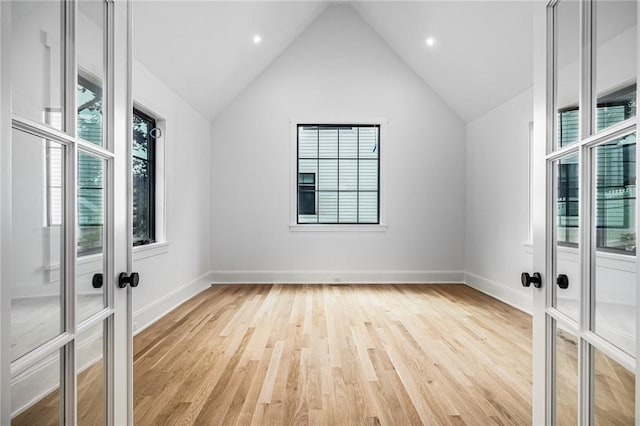 unfurnished room with lofted ceiling, french doors, baseboards, and light wood finished floors