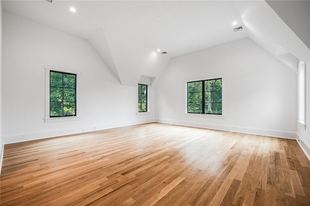 interior space featuring vaulted ceiling, light wood-style flooring, visible vents, and baseboards