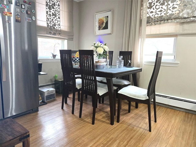 dining space featuring a baseboard radiator, light hardwood / wood-style floors, and a healthy amount of sunlight