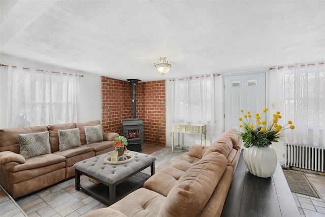 living room featuring a healthy amount of sunlight, radiator, a wood stove, and a textured ceiling