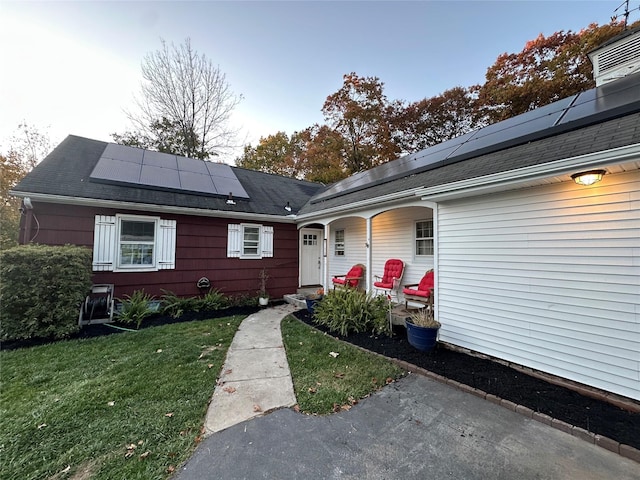 view of front of property featuring a front yard, solar panels, and a porch