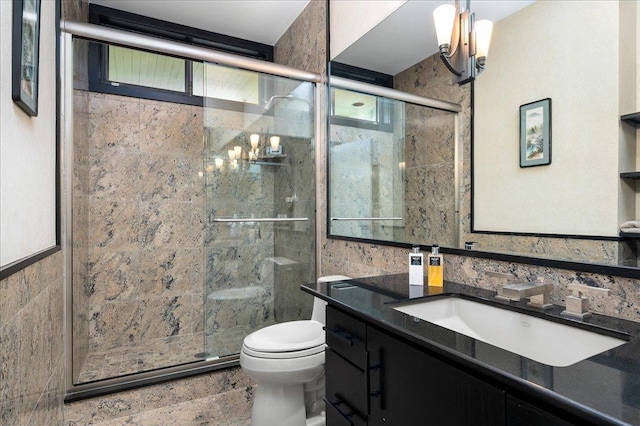 bathroom with tile walls, vanity, a shower with door, and toilet