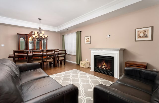 living room with wood-type flooring, crown molding, an inviting chandelier, and a tray ceiling