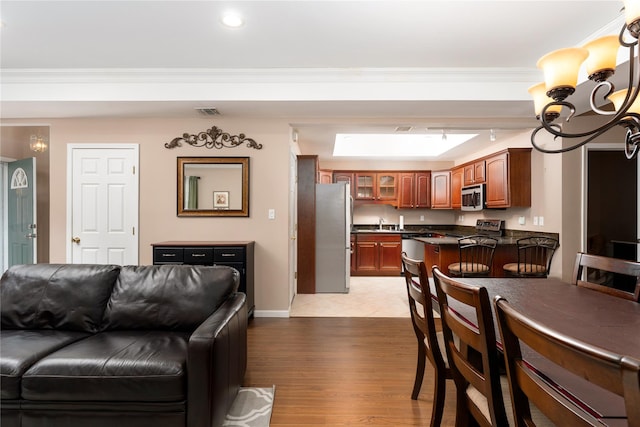 interior space featuring a notable chandelier, ornamental molding, sink, and light hardwood / wood-style flooring