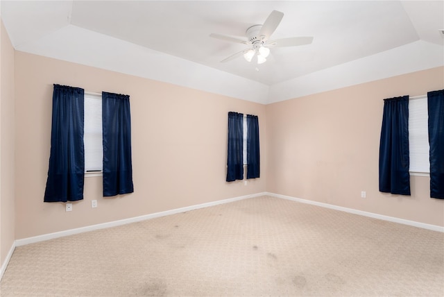 carpeted spare room featuring lofted ceiling, ceiling fan, and a raised ceiling