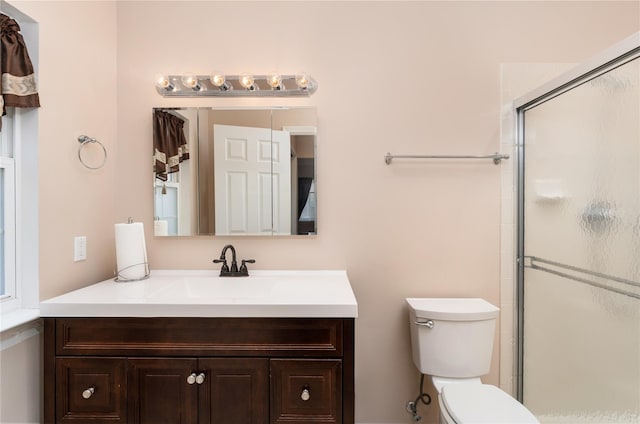 bathroom with vanity, toilet, and a shower with door