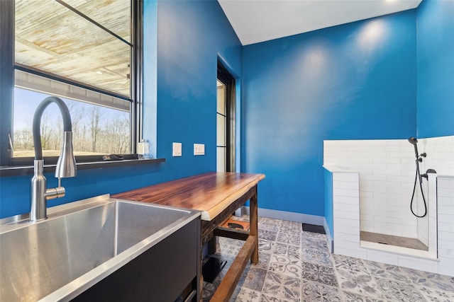 interior space with baseboards, a sink, a tile shower, and tile patterned flooring